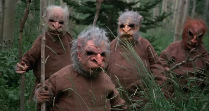 Group of creepy characters in monster costumes standing in a forest scene from worst-best movies people enjoy.