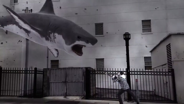 Scene from worst-best movies showing a large shark attacking a person near an urban fence at night.