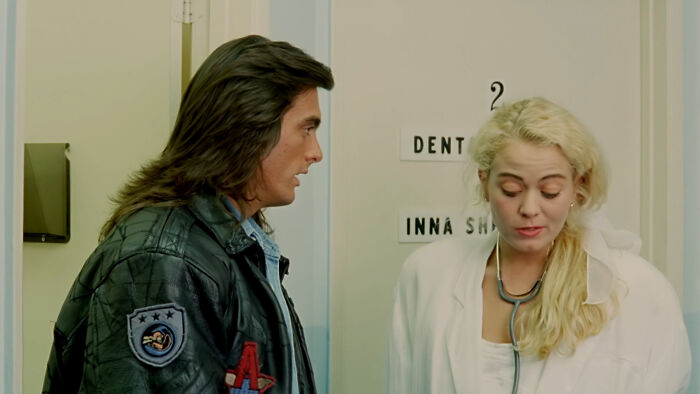 Scene from a worst-best movie showing a man in a leather jacket talking to a woman in a white coat with a stethoscope.