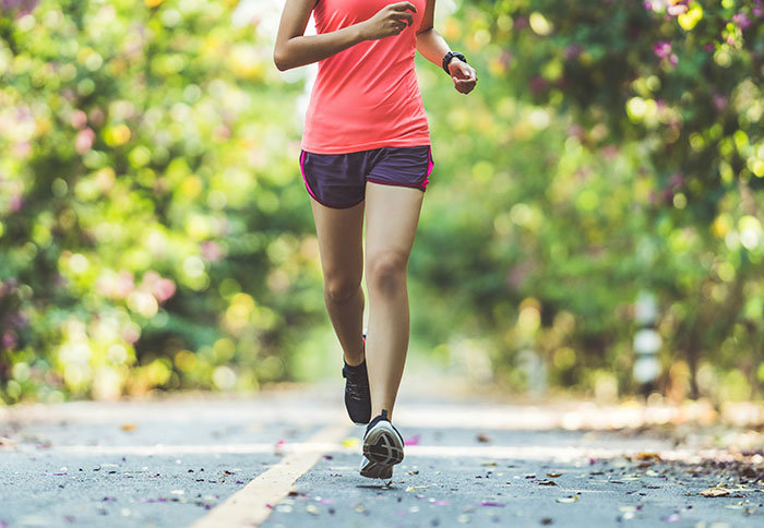 Person running outdoors on a quiet road surrounded by trees, illustrating trusting instincts for safety and awareness.