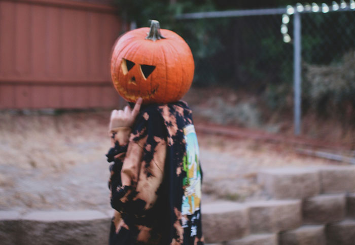 Person wearing a carved pumpkin on their head, symbolizing instincts and thankful moments captured outdoors.