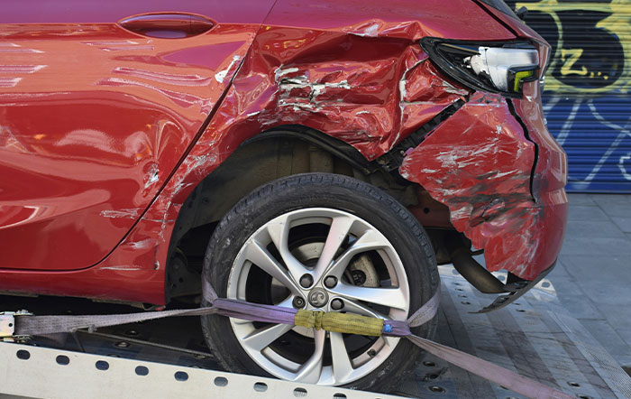 Red car with severe rear damage secured on a tow truck, illustrating situations where listening to instincts prevented harm.