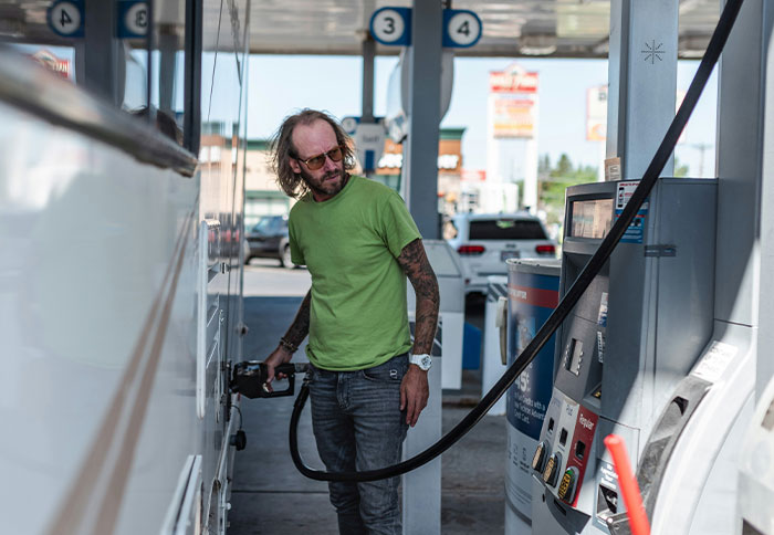 Man in a green shirt filling gas at a station, illustrating moments when people trusted their instincts and avoided danger.