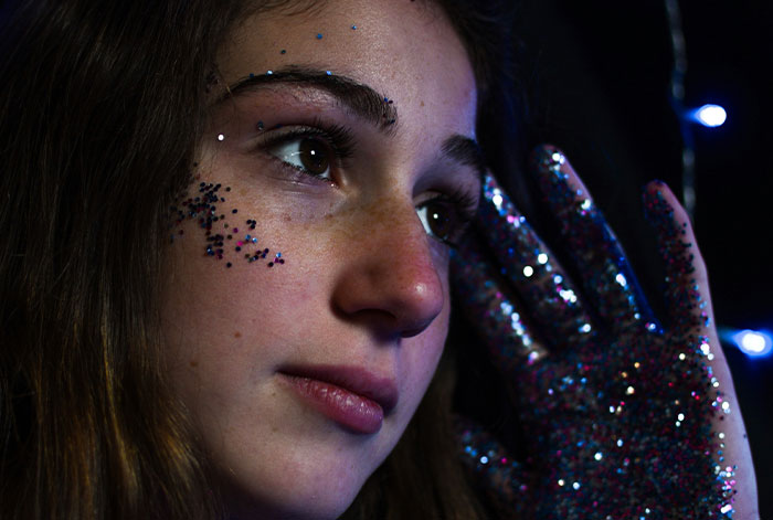 Young woman with glitter on her face and hand, illustrating the theme of people thankful they listened to instincts.