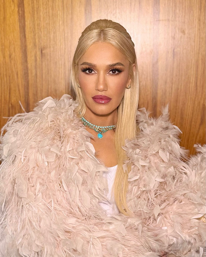 Blonde woman with feathered coat and turquoise necklace, styled in a new look fans mistake for Jennifer Lopez or Gwen Stefani.
