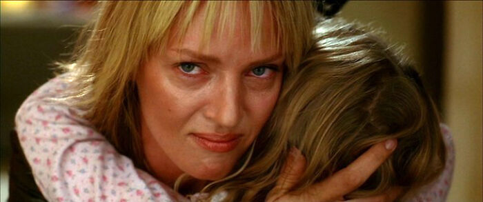 Woman with blonde hair embracing a child, portraying well-written female characters in movies breaking stereotypes.