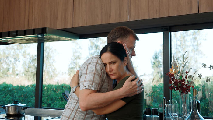 Middle-aged couple embracing in a kitchen, showing emotional support as the woman reflects on her short haircut experience. Middle-aged couple embracing in a kitchen, showing emotional support as the woman reflects on her short haircut experience.