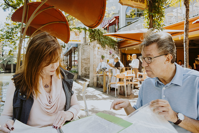 Middle-aged man and woman discussing documents outdoors, reflecting strained stepdad and stepkids inheritance conflict.