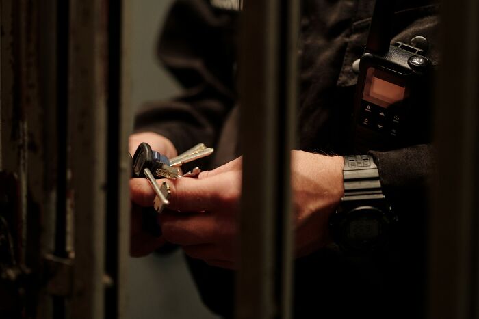 Police officer holding keys behind prison bars, illustrating wrongful blame in innocent people cases.
