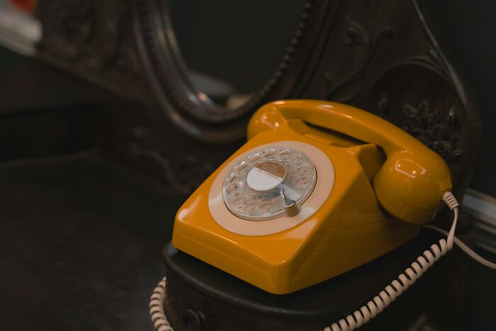 Vintage yellow rotary phone on a dark wooden surface representing unexplained mysteries from the dawn of the internet.