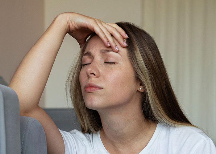 Woman looking stressed and frustrated indoors, reflecting on canceling friend&rsquo;s holiday booking after harassment issue.