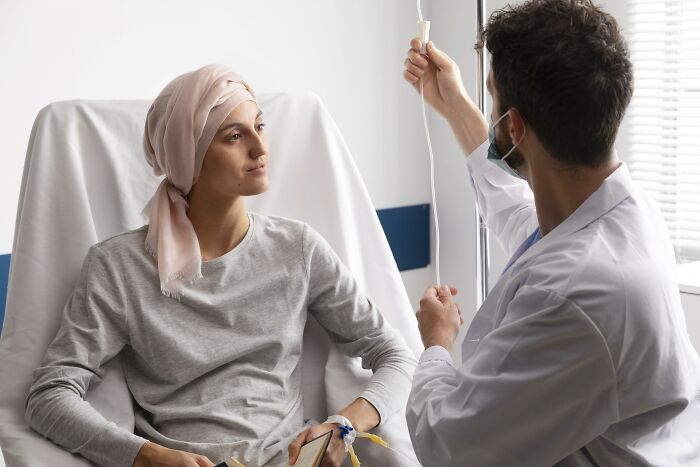Doctor adjusting IV drip while nurse patient wearing headscarf receives treatment, illustrating doctors and nurses experiences.