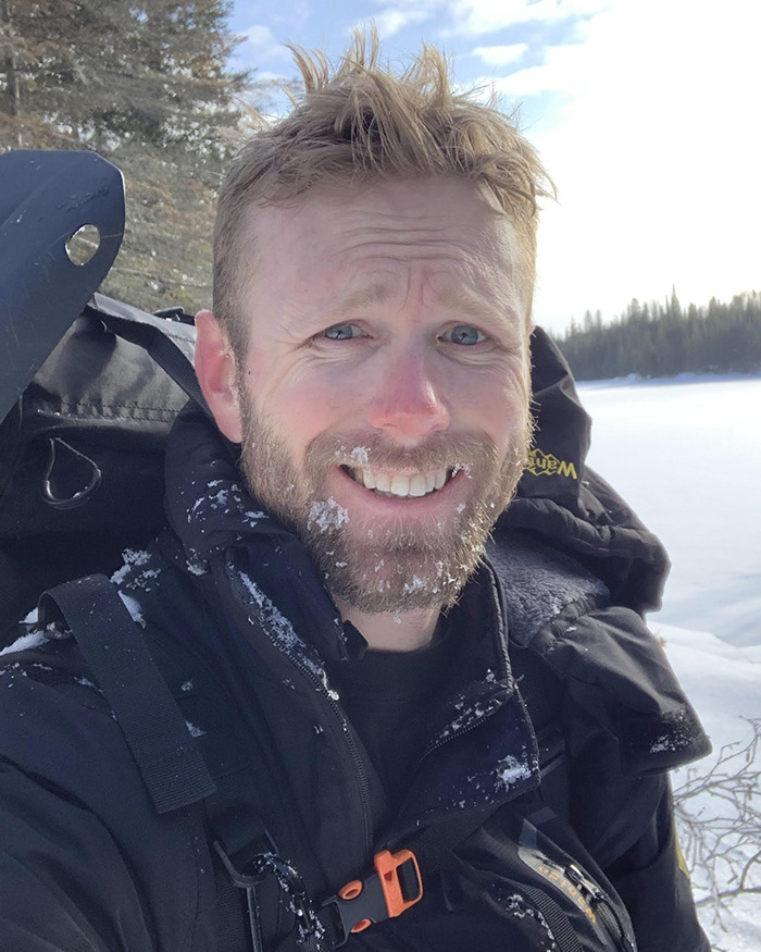 Hiker in snowy mountain gear with frost on beard, smiling during a cold outdoor expedition at high altitude. Hiker in snowy mountain gear with frost on beard, smiling during a cold outdoor expedition at high altitude.