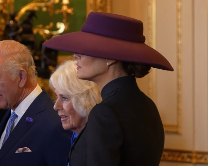 Melania Trump wearing a large purple hat and black outfit, showcasing wardrobe choices during UK state visit event. Melania Trump wearing a large purple hat and black outfit, showcasing wardrobe choices during UK state visit event.