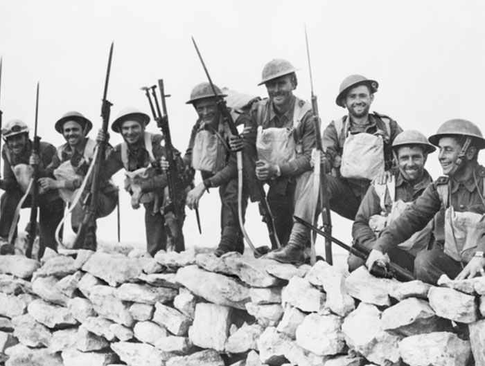 Black and white historic photo of soldiers with rifles and bayonets behind a stone wall, a weird and iconic bruh moment in history.