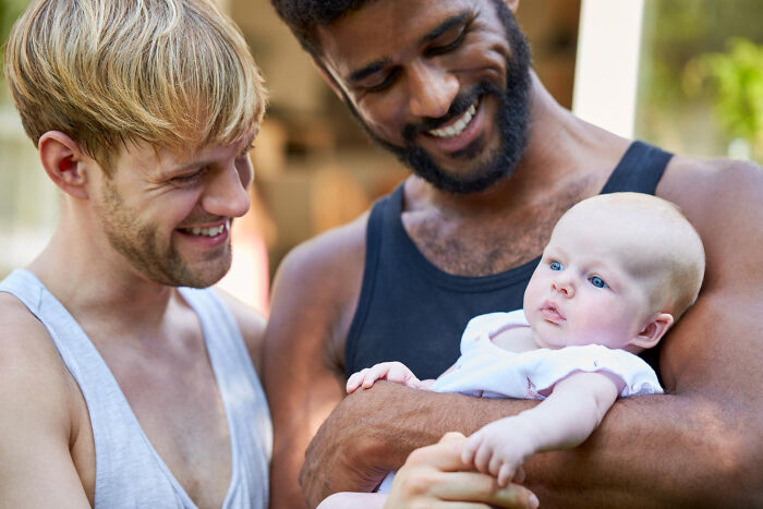Two men smiling warmly at a baby, illustrating signs of the worst partner ever in relationships.