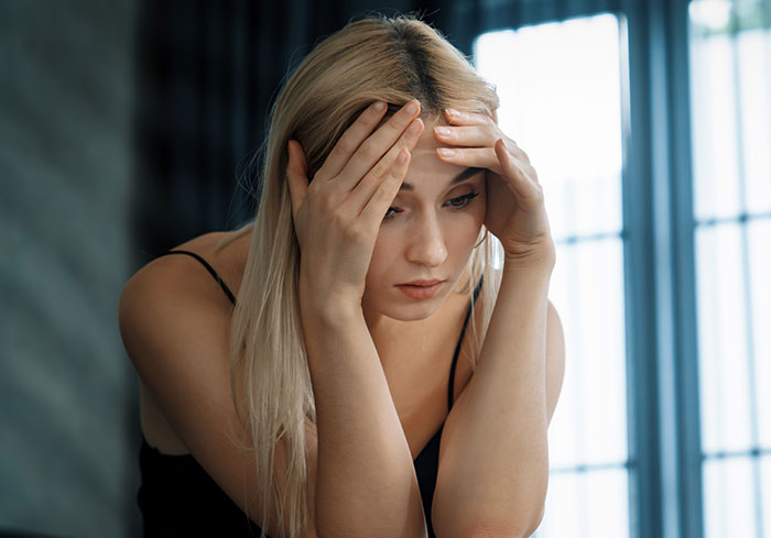 Stressed woman holding her head, feeling overwhelmed by husband expects wife work study full time and two kids demands.