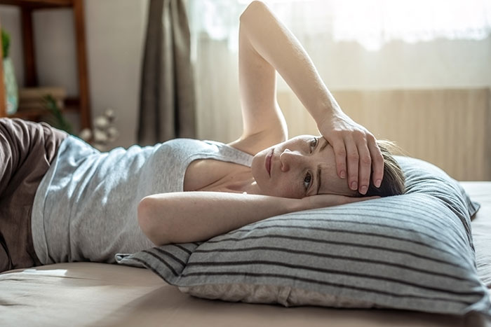 Woman lying on bed looking distressed and exhausted, illustrating feelings of being left behind and ignored by her partner.