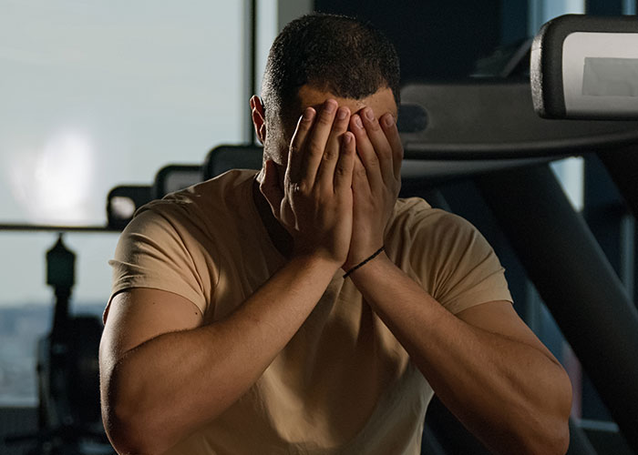 Man covering face with hands in dimly lit room, depicting emotional stress around intimacy boundaries and divorce predictions.