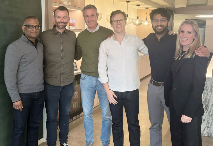 Group of six people smiling indoors, representing Coldplay KissCam saga involving HR exec&rsquo;s husband attending concert with a date.