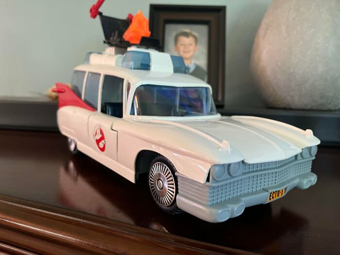 Vintage toys worth fortune featuring a detailed Ghostbusters Ecto-1 collectible car on a wooden surface.