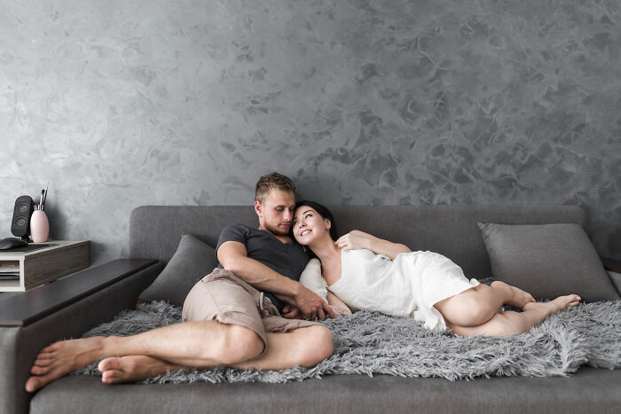 Couple relaxing on a gray sofa in a cozy modern living room, highlighting women sharing reasons for getting the ick from a guy.