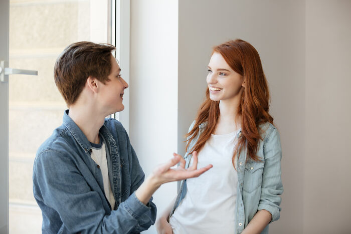 Two young people smiling and talking by a window, illustrating reasons women get the ick from a guy.
