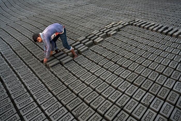 Man arranging bricks in a large field, showcasing everyday life in India through this photographer’s captured moment.