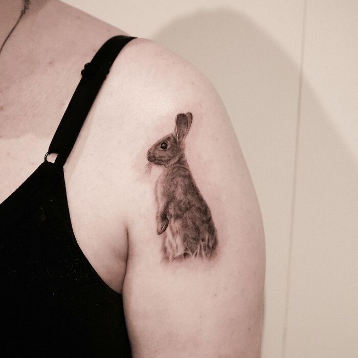 Realistic pet tattoo of a rabbit on upper arm by Korean tattoo artist known for emotional pet tattoos.