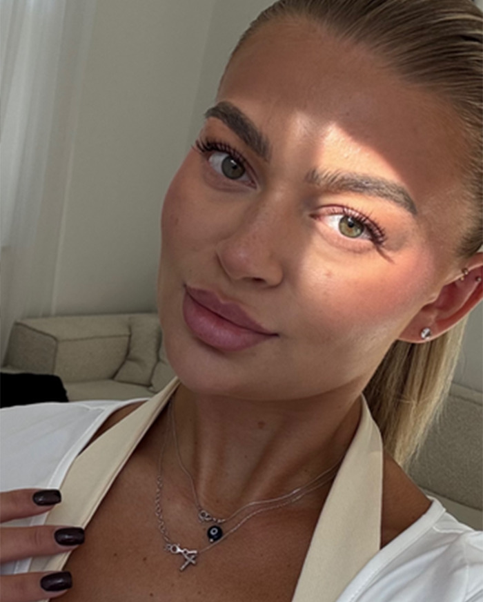 Young woman indoors with polished makeup and jewelry, engagement post going viral for all the wrong reasons. Young woman indoors with polished makeup and jewelry, engagement post going viral for all the wrong reasons.