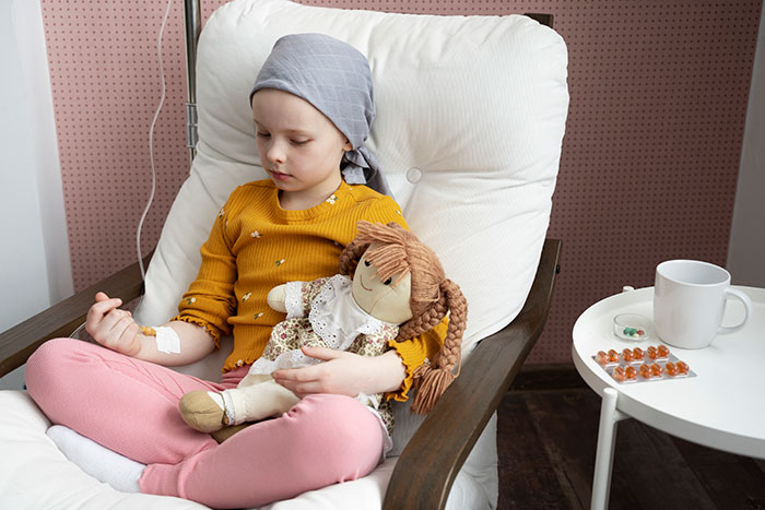 Child wearing a headscarf sitting with a doll, receiving medical treatment, illustrating fascinating knowledge about health facts.