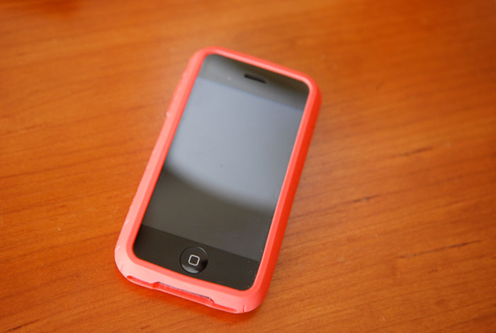 Smartphone with a red case lying on a wooden surface, representing daily dose of useless yet fascinating knowledge concept.