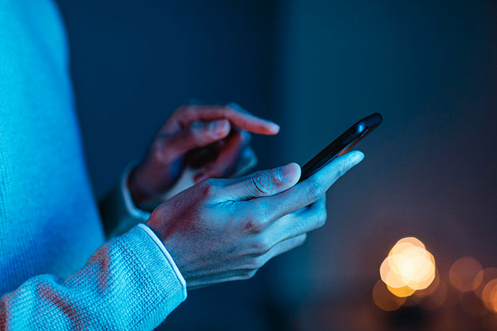 Person using smartphone at night, highlighting daily dose of fascinating knowledge facts on mobile device screen.
