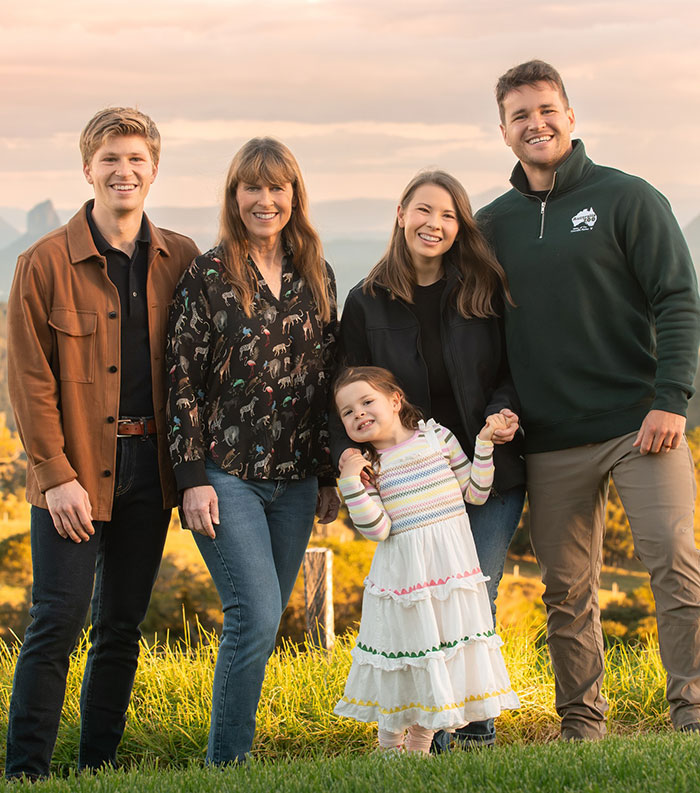 Bindi Irwin smiling with family outdoors at sunset, announcing surprising decision as she leaves Australia. Bindi Irwin smiling with family outdoors at sunset, announcing surprising decision as she leaves Australia.