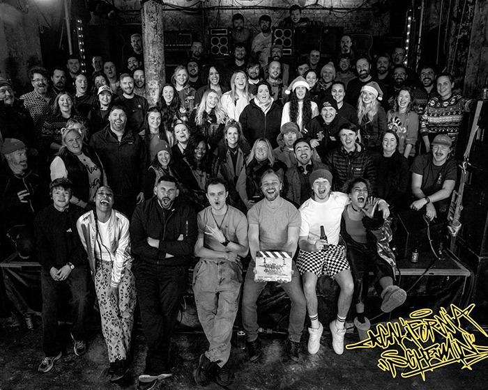 Large group of people smiling and posing together, celebrating James McAvoy&rsquo;s directorial debut in a casual setting.