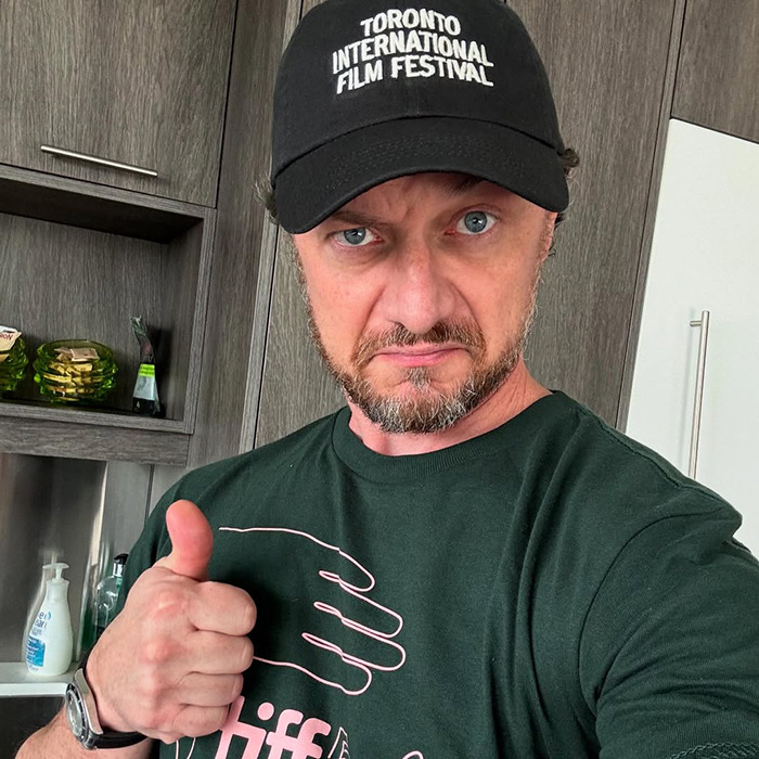 Man wearing Toronto International Film Festival cap and green shirt giving thumbs up, related to James McAvoy sucker punched news.