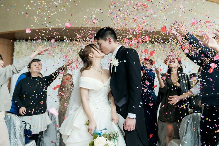 Newlywed couple kissing while guests celebrate with confetti, symbolizing happy marriages and great relationship tips.