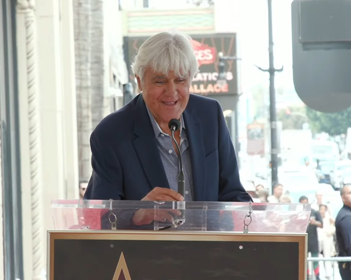 Jay Leno speaking at a podium outdoors, reacting to Jimmy Kimmel's suspension after offensive Charlie Kirk comments