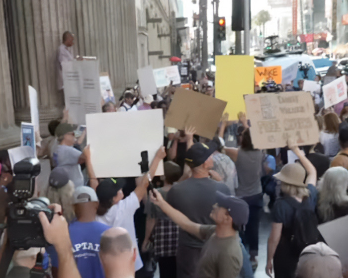 Crowd gathered on city street holding protest signs as Jay Leno reacts to Jimmy Kimmel suspension after offensive Charlie Kirk comments