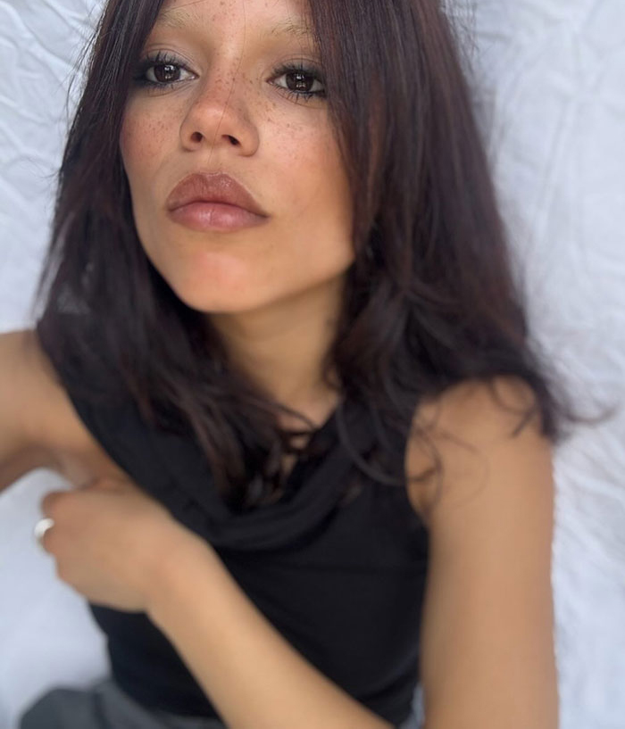 Close-up of Jenna Ortega showcasing her bold diamond-encrusted look with natural makeup and loose dark hair. Close-up of Jenna Ortega showcasing her bold diamond-encrusted look with natural makeup and loose dark hair.