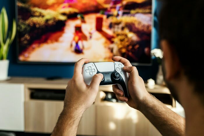 Adult playing video games with a controller in a living room, illustrating adults who failed to understand growing up.