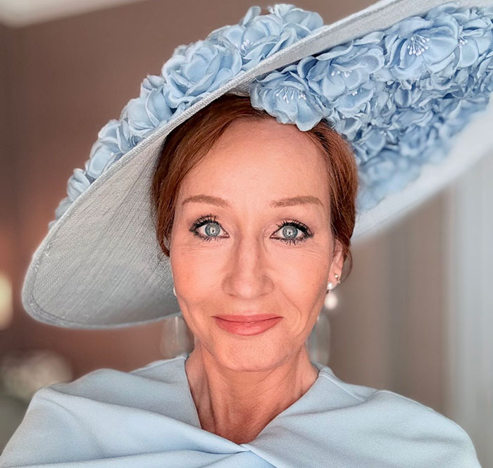 J.K. Rowling wearing a large blue floral hat and matching outfit, addressing viral cancer rumor and public reactions. J.K. Rowling wearing a large blue floral hat and matching outfit, addressing viral cancer rumor and public reactions.