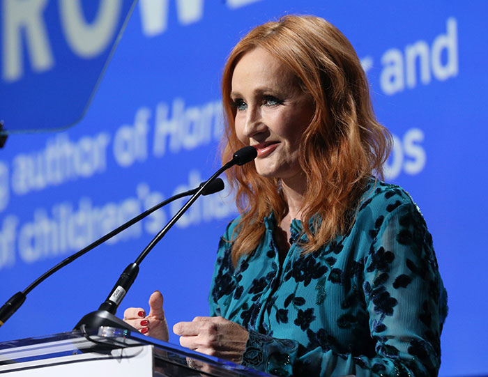 J.K. Rowling speaking at a podium during an event as her team breaks silence on viral cancer rumor. J.K. Rowling speaking at a podium during an event as her team breaks silence on viral cancer rumor.