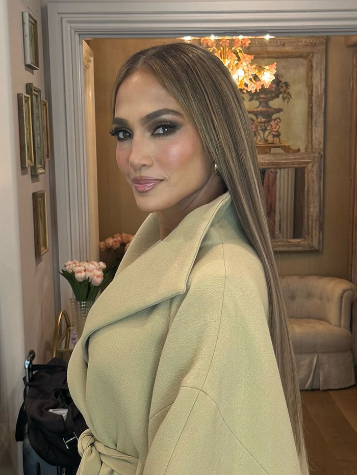 Jennifer Lopez with long straight hair and beige coat, fans mistake her for Gwen Stefani in new look indoors.