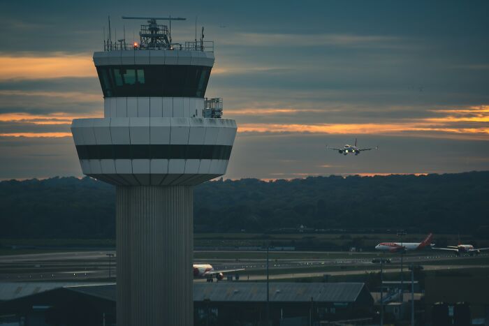 Air traffic control tower at dusk with planes landing and taking off, illustrating impressions that receive hilarious reviews.
