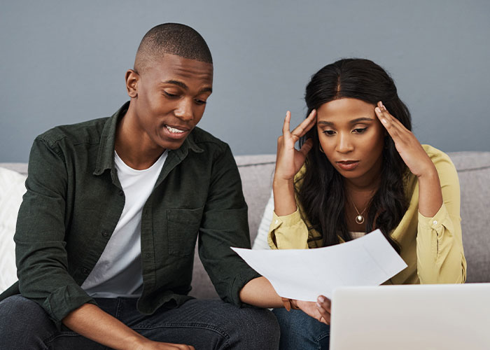 Couple discussing plans and paperwork together, possibly related to choosing a white wedding dress for their event.