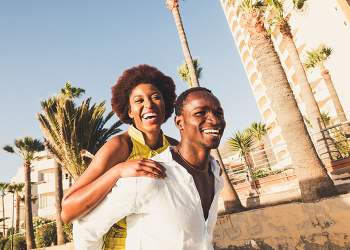 Happy couple outdoors near palm trees, with focus on joyful moment and a white wedding dress theme.
