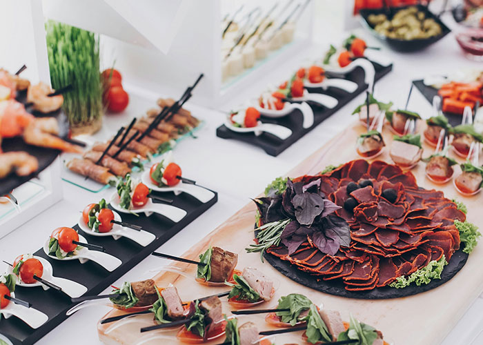 Assorted elegant appetizers served on a white table at a wedding reception featuring a white wedding dress theme.