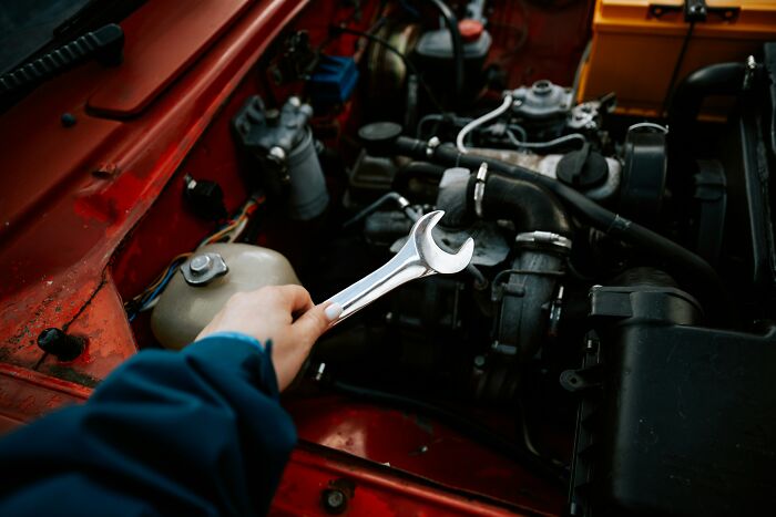Person holding a wrench working on a car engine illustrating companies that sabotage their own products.