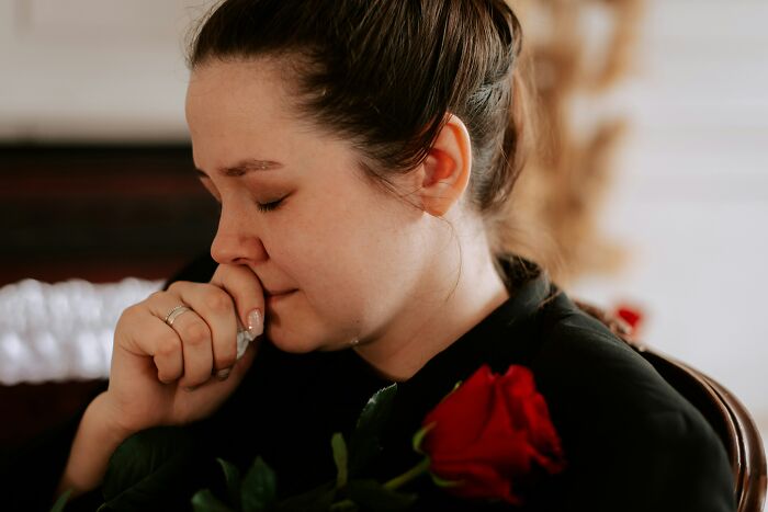 Woman grieving while holding a red rose, reflecting on the suspicious combination of butcher and gravedigger professions.